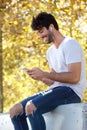 Smiling handsome man sitting outside with headphones and mobile phone Royalty Free Stock Photo