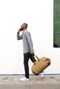 Side portrait of traveling young african man walking and talking on cell phone Royalty Free Stock Photo