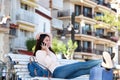 Side portrait of woman sitting outside with phone and luggage Royalty Free Stock Photo