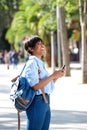 Side portrait young black woman walking outside with mobile phone Royalty Free Stock Photo