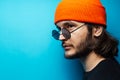 Side portrait of young man on  blue background. Wearing sunglasses and hat. Royalty Free Stock Photo