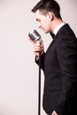 Side portrait of young man in suit singing with the microphone Royalty Free Stock Photo