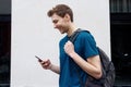 Side of young man walking with mobile phone and bag Royalty Free Stock Photo
