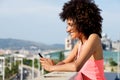 Side portrait of young woman with headphones outside holding mobile phone Royalty Free Stock Photo