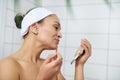 Side portrait of a young woman wearing lipstick with a brush holding a small mirror Royalty Free Stock Photo