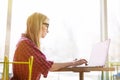 Side portrait young woman worker sitting in office while using laptop computer and typing by keyboard Royalty Free Stock Photo