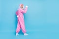Side profile full size photo of cheerful elderly pensioner wear pink bunny costume demonstrating biceps isolated on blue