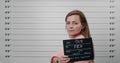 Side profile mugshot of arrested young woman with long hair turning head and looking to camera. Crop view of female