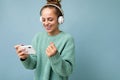 Side-profile photo of attractive emotional positive young woman wearing blue sweater isolated over blue background