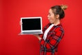 side profile photo of Beautiful shocked amazed young woman holding laptop wearing red shirt looking at monitor display