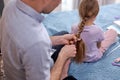 side profile photo father making braids to little girl in morning at home