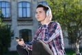 Side profile turned photo of concentrated guy enjoying cool clear sound from his new headset sitting on grass
