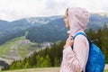 Side profile view of attractive beautiful girl, wearing casual rose jacket and blue rucksack, female backpacking and wandering.