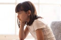 Side view preschool adorable girl sitting on couch at home Royalty Free Stock Photo