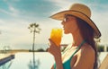 Woman wear straw hat drinks orange juice relaxing near pool Royalty Free Stock Photo