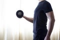 Side profile view photo of sportive strong muscular guy building muscles on arms by lifting dumbbells, black sportive clothes