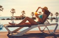 Woman in bikini drinks cocktail sunbathing on deckchair near pool Royalty Free Stock Photo