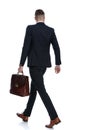 Side rear view of businessman holding briefcase and walking Royalty Free Stock Photo