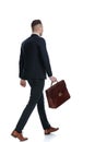 Side rear view of businessman holding briefcase and walking Royalty Free Stock Photo