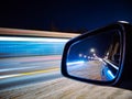 In the side rear-view mirror of the car, the evening road and lights are reflected Royalty Free Stock Photo