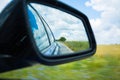 Side rear-view mirror car reflection of a countryside road Royalty Free Stock Photo