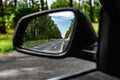 Side rear-view mirror of modern car with forest landscape. Royalty Free Stock Photo