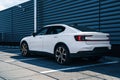 Side rear view of Snow White Polestar 2 parked in the shade in front of metal building