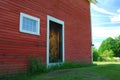 Side of red wood barn with wooden door and 8 pane window Royalty Free Stock Photo