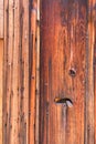 The side of a redwood house has vertical and horizontal planks