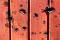 Side of shipping container rusted metal plate heavily damaged by shrapnel during war covered with faded dilapidated paint