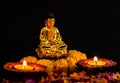 Side shot of beautilful buddha statue with two clay lamps and colorful flowers on black background. religion concept Royalty Free Stock Photo