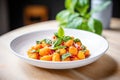 side shot of gnocchi in tomato sauce with a basil leaf