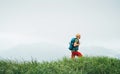 Side shot of hiker man walking by the foggy cloudy weather mountain range path with backpack. Active sport backpacking healthy Royalty Free Stock Photo