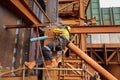 Side shot of industrial rope access welder maintenance abseiler wearing fall safety body harness helmet protective equipm