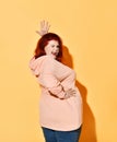 Side shot of joking positive chubby young female standing with hands on hips, giving a wink and lolling. Royalty Free Stock Photo