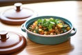 side shot of lamb tagine with open lid, on wood surface