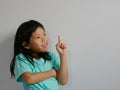 A side-shot portrait of surprised, excited, little girl, 5 years old, pointing her finger up on a white blank background, copy Royalty Free Stock Photo