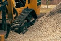 Side of the stump grinder with tracks and a pile of chips next to it