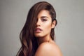 Side swept hair looks stunning. Studio shot of a young beautiful woman with long gorgeous hair posing against a grey