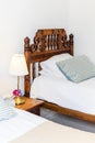 Bedside table with white lamp in the bedroom with vintage wooden bed