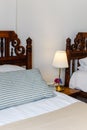 Bedside table with white lamp in the bedroom with vintage wooden bed