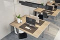 Side top view on eco style workspaces with modern computers on wooden tables in coworking office with concrete floor and light Royalty Free Stock Photo