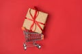 Side top view photo of small mini metal pushcart riding with large gift inside isolated bright red background Royalty Free Stock Photo