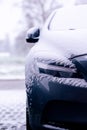 The side of a vehicle starting to get snowed under during a blizzard. The snow already covers the windshield of the car making it