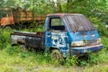 Side view of an abandoned blue pick up vehicle stay strong with a truck in the background