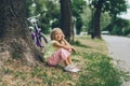 side view of adorable smiling kid resting near bicycle under tree Royalty Free Stock Photo