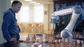 Side view of an adult man playing chess with a robotized arm