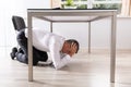 Afraid Businessman Hiding Under Table
