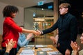 Side view of African American businesswoman and Caucasian businessman shaking hands after signing contract, members of Royalty Free Stock Photo