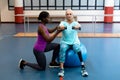 Trainer assisting disabled senior woman to exercise with dumbbell in sports center Royalty Free Stock Photo